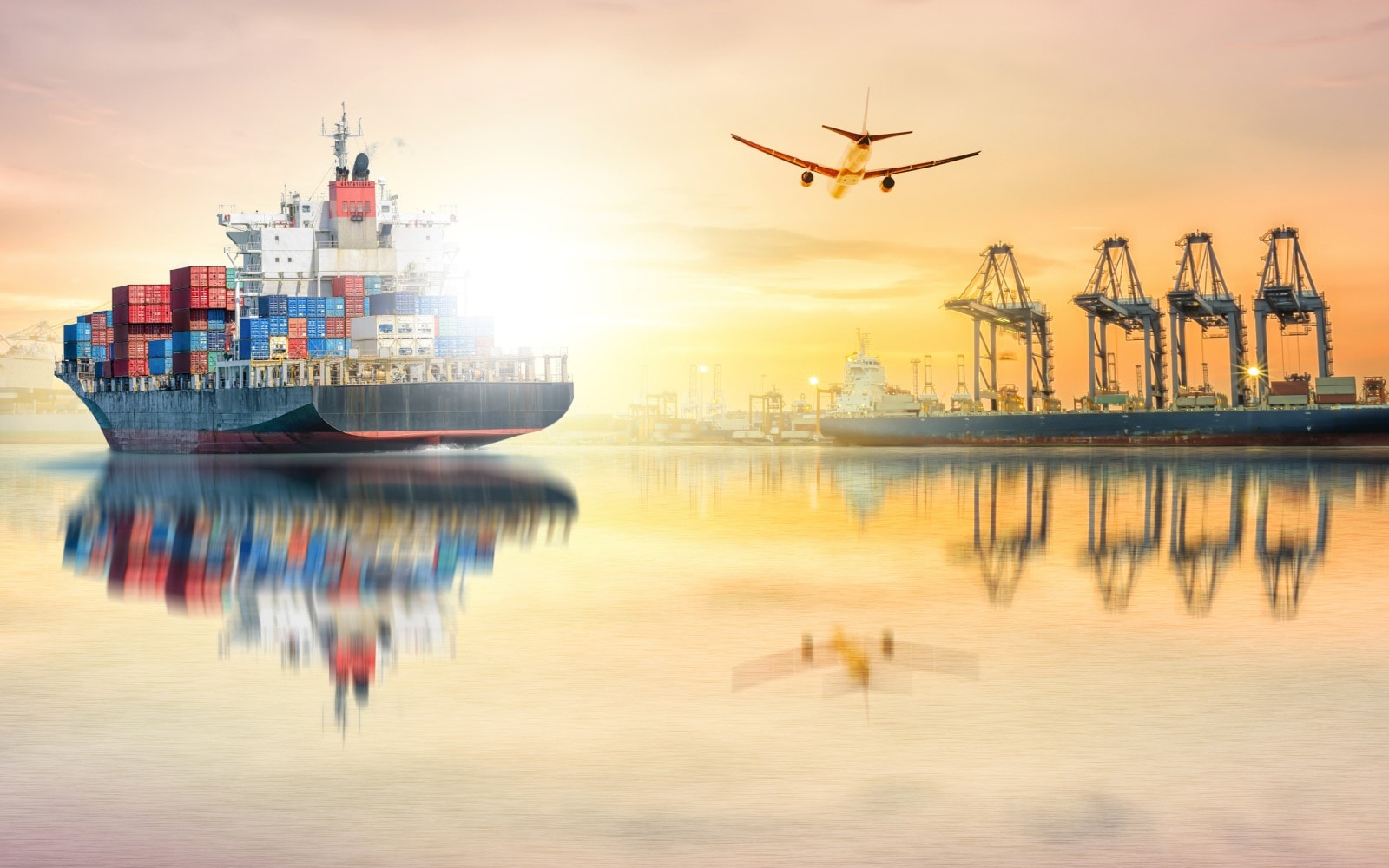 Freight ship, plane, and ocean port at sunset