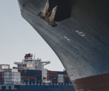 Close up of side of ship with container ship in background