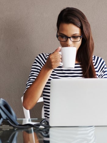 Woman sipping coffee at computer