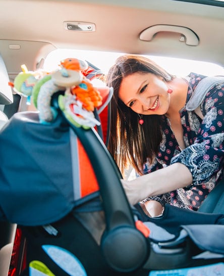 Woman preparing to load child in car seat