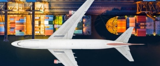 Cargo plane flying over container ships