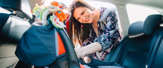 Woman preparing to load child in car seat