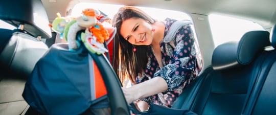 Woman preparing to load child in car seat