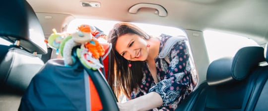 Woman preparing to load child in car seat