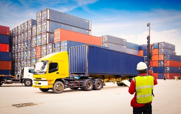 Freight truck in front of stacked freight containers