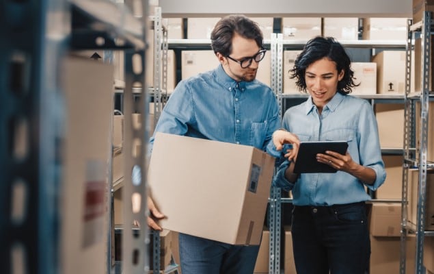 Man carrying box working with woman using tablet