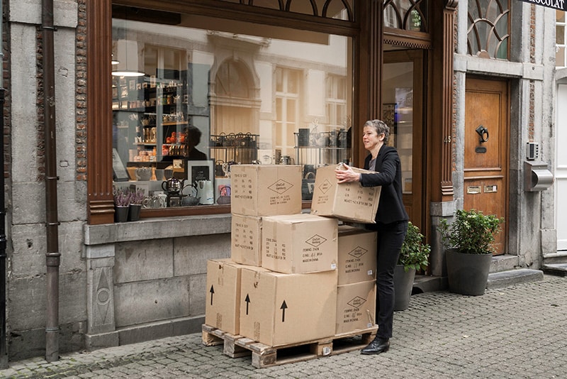 Female shop owner unloading a palette of boxes outside her shop